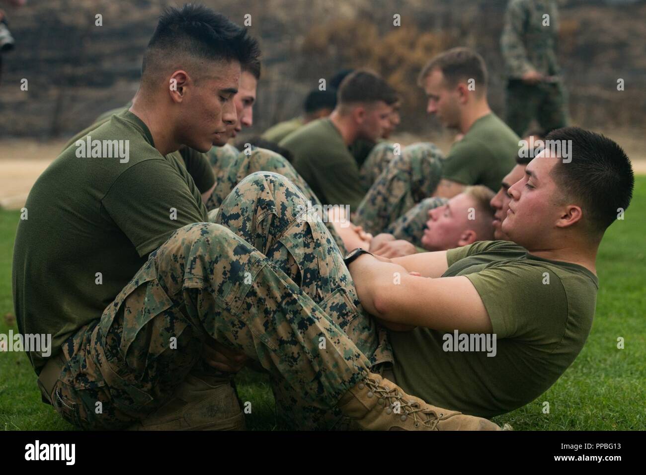 U.S. Marine Corps Cpl. David Avila left assists Pfc. Alec Jimenez both riflemen with 3rd Battalion 5th Marine Regiment in sit ups during the physical fitness test portion of the 1st Marine