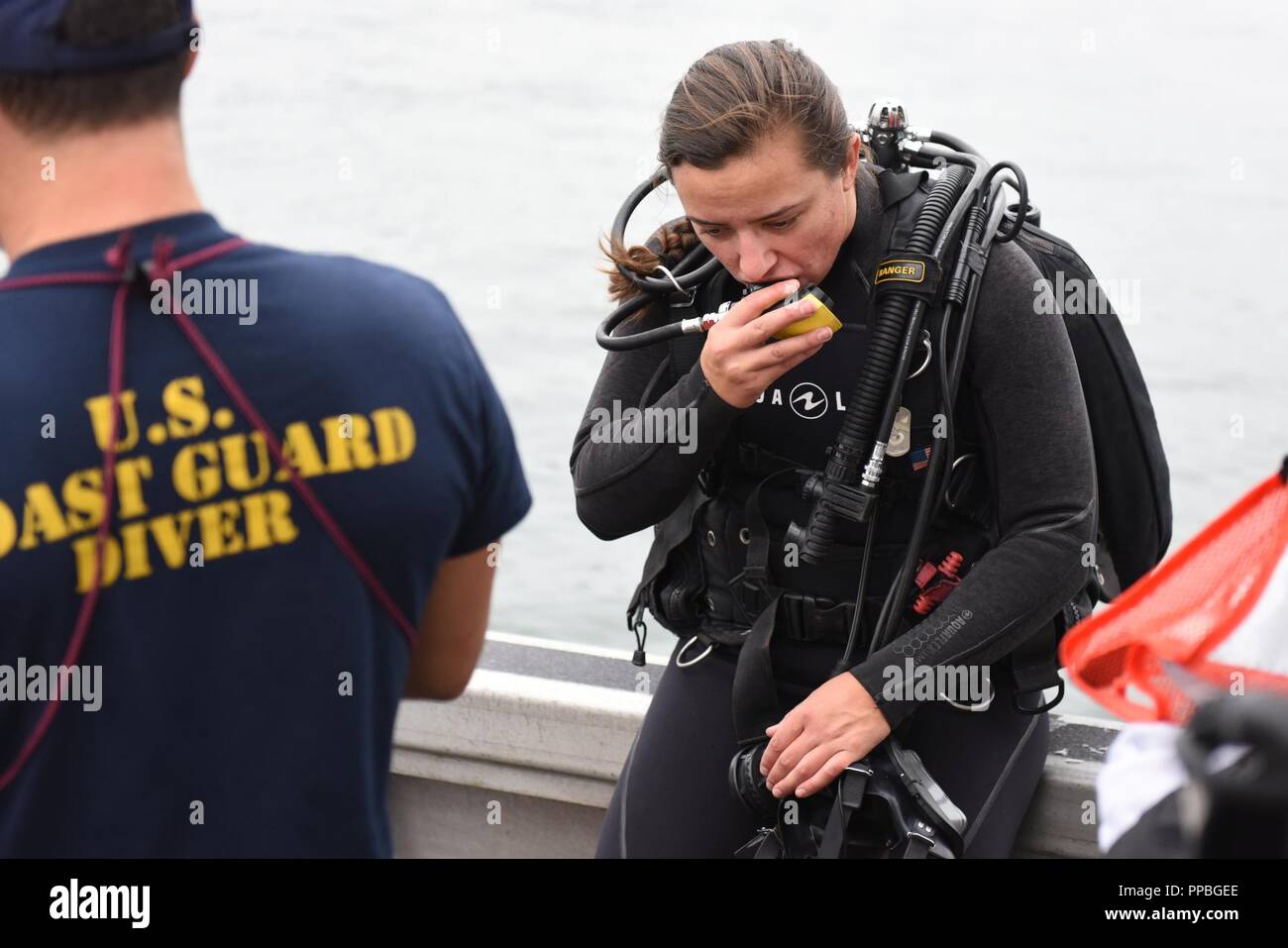 Petty Officer 2nd Class Monique Gilbreath, a diver from the Coast Guard Regional Dive Locker West, Maritime Security Response Team West, checks her equipment prior to entering the water along North Harbor Drive, San Diego Aug. 25, 2018. The dive team was participating in Operation Clean Sweep 2018, a community cleanup effort along the San Diego Bay. Stock Photo