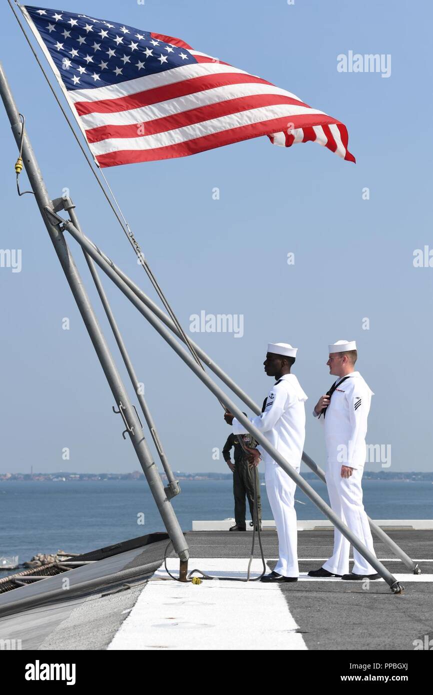 NORFOLK (Aug. 28, 2018) Information Systems Technician Seaman Wesley Iles, right, and Airman Recruit Nathaniel Graszler prepare to lower the national ensign as the Nimitz-class aircraft carrier USS Harry S. Truman (CVN 75) departs Naval Station Norfolk, Aug. 28, 2018. Harry S.  Truman will continue its deployment by conducting sustainment operations in the Atlantic. Stock Photo