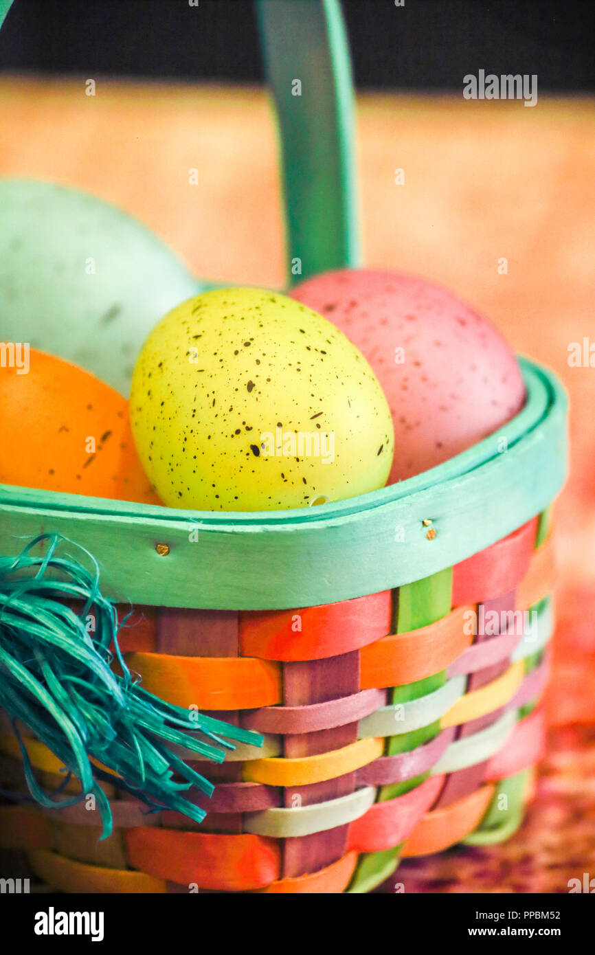 Colorful easter eggs in easter basket vertical over orange background. Stock Photo