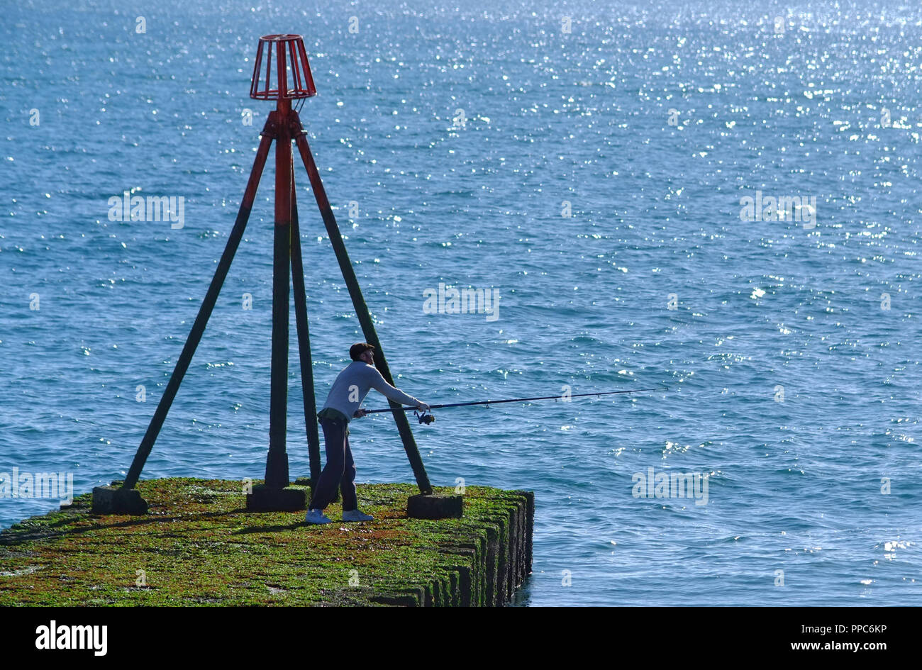 Man sea fishing on a pier, Splash Point, Seaford, Uk Stock Photo