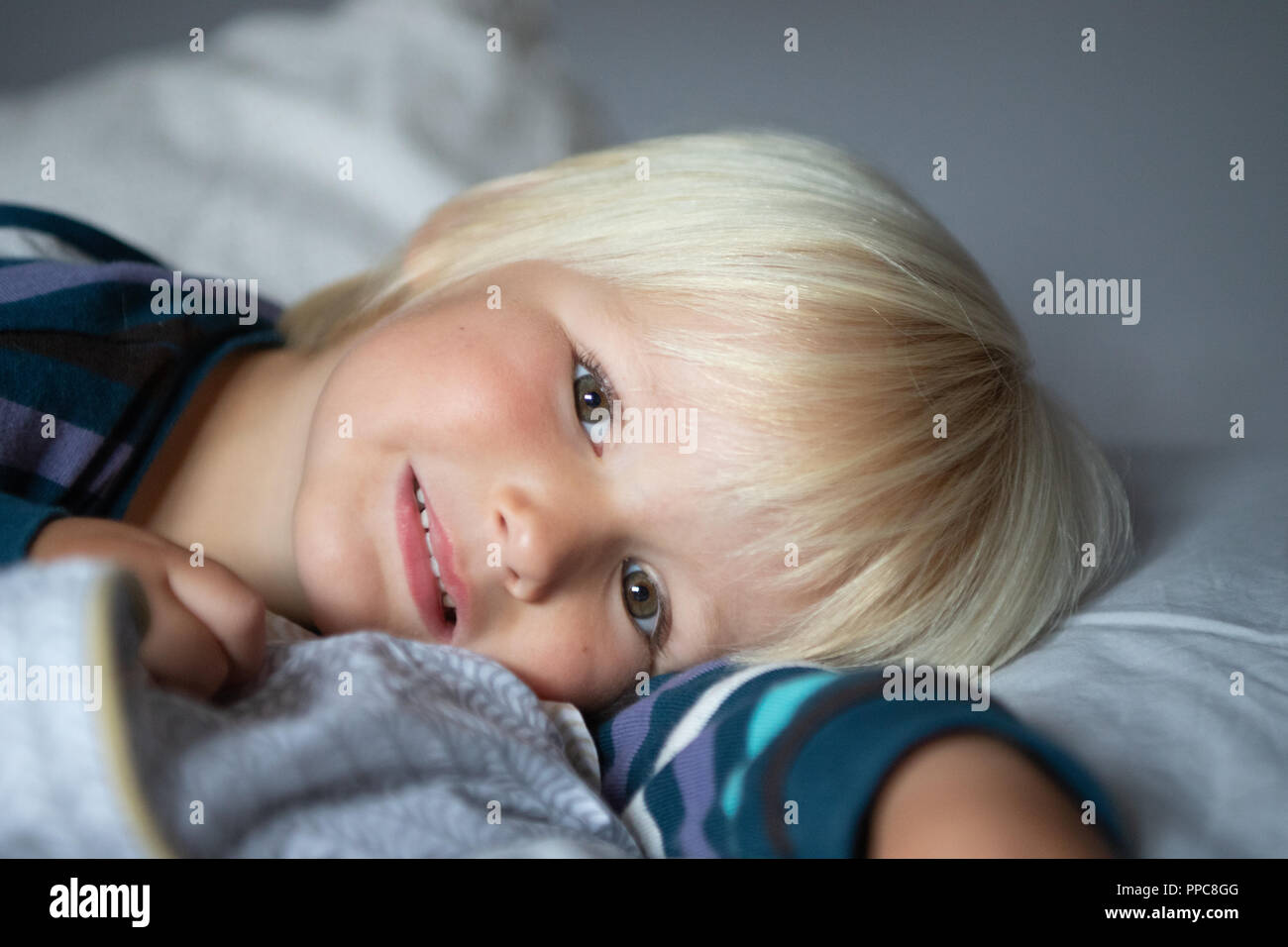 smiling boy laying down with blond hair brown eyes Stock Photo