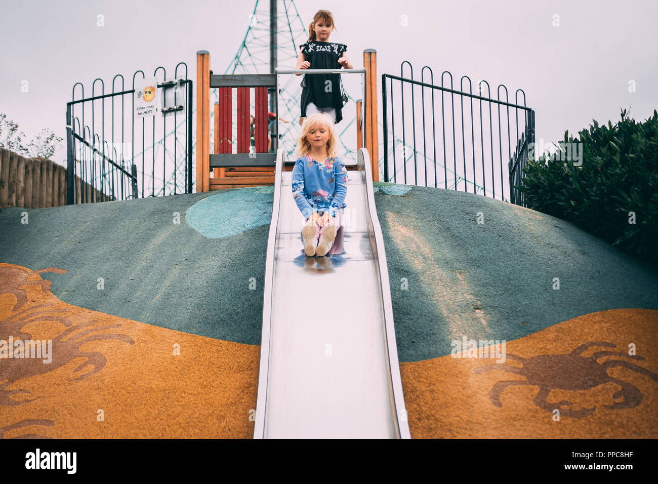 blonde girl play on slide in play park Stock Photo