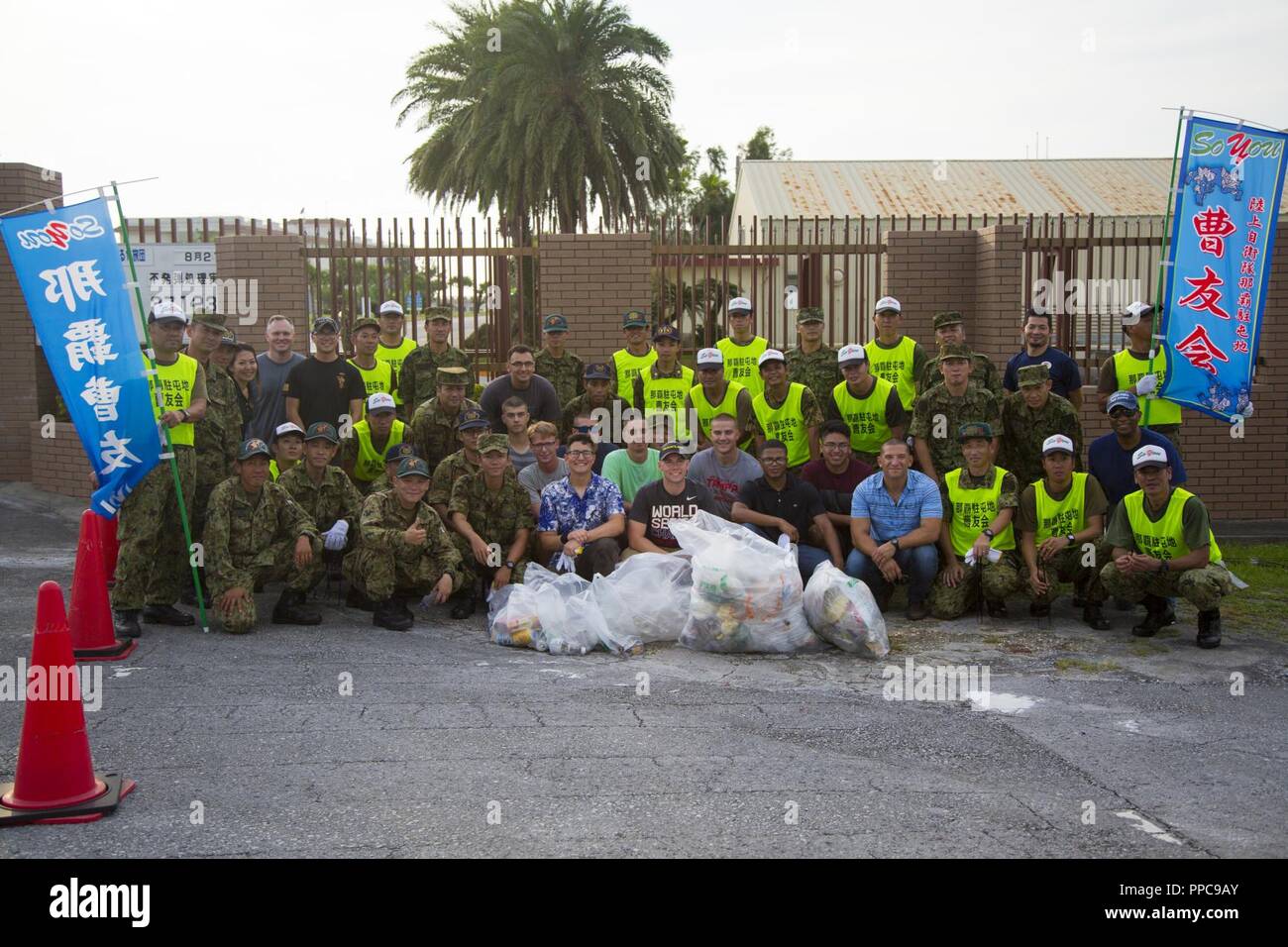 NAHA, OKINAWA, Japan- Japan Ground Self-Defense Force service members and members of the Single Marine Program Pose for a photo Aug 21 after a cleanup around the perimeter of Camp Naha, Okinawa, Japan. The cleanup allowed JGSDF and members of the SMP a chance to meet each other while also cleaning up the city. This was the first time the SMP conducted a cleanup at Camp Naha and plans to make it a regular event. Stock Photo