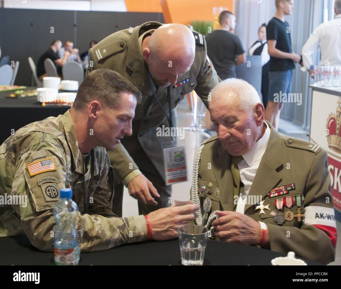 U.S. Army Lt. Col. Matthew Rogers, right, the commander of the 91st Engineer Battalion, 1st Armored Combat Brigade Team, 1st Calvary Division, gives a token of appreciation to a veteran of the 1939 Warsaw Uprising during his attendance of a Zagłębie Lubin soccer game in celebration of military appreciation night held in Lubin, Poland, Aug. 12, 2018. Polish army Maj. Jacob Wołynski, center, the athletic director with the 23rd Artillery Regiment, assisted in organizing the event for Polish and U.S. military personnel in honor of Polish Army Day. Stock Photo