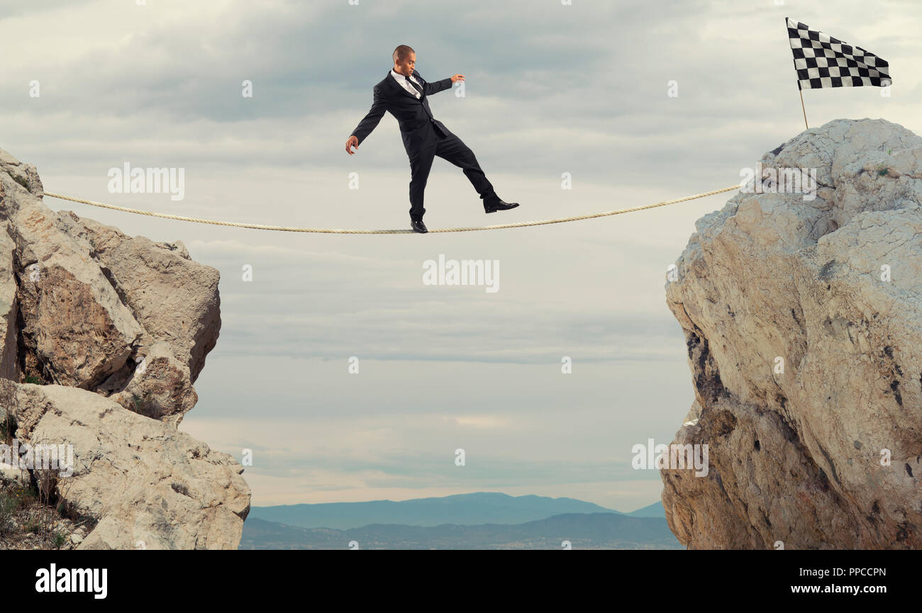 Business concept of businessman who overcome the problems reaching the flag on a rope Stock Photo