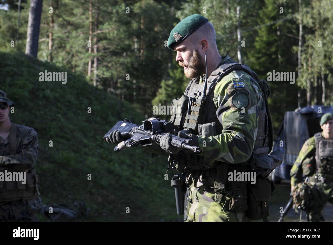 A Swedish Coastal Ranger with 1st Marine Regiment explains the capabilities of the Swedish Automatkarbin 5 service rifle during a cross-training range at Exercise Archipelago Endeavor aboard Berga Naval Base, Harsfjarden, Sweden, Aug. 22, 2018. Exercise Archipelago Endeavor is an integrated field training exercise that increases operational capability and enhances strategic cooperation between the U.S. Marines and Swedish forces. Stock Photo
