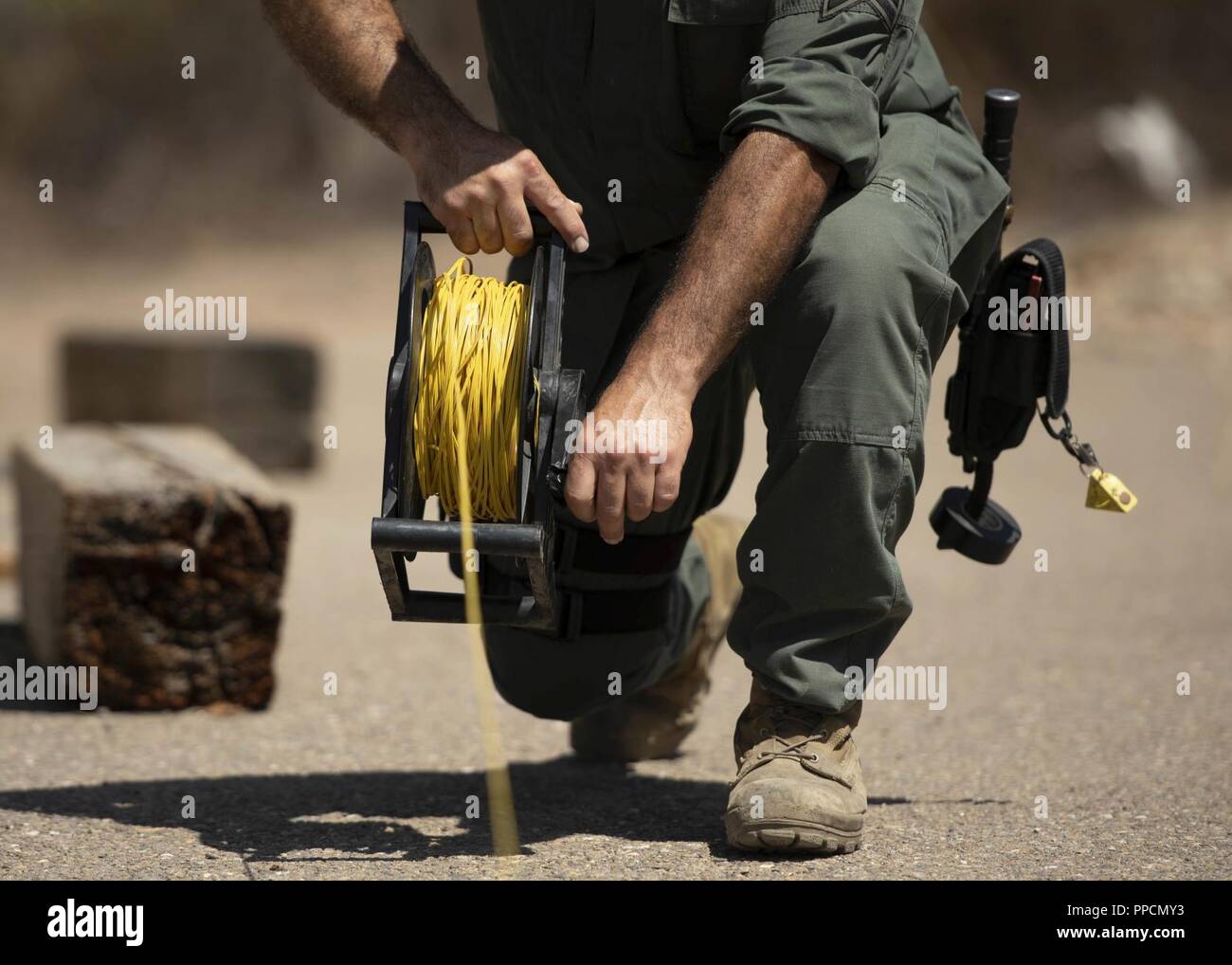 A bomb technician reels in a fuse used to ignite explosions during