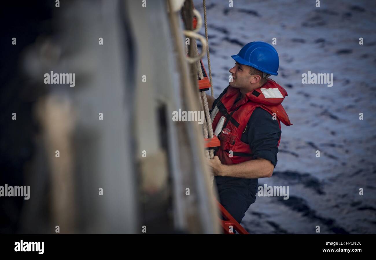 SEA (Aug. 29, 2018) Lt. j.g. Chris Smith climbs aboard the Arleigh Burke-class guided-missile destroyer USS Carney (DDG 64) from a rigid-hull inflatable boat Aug. 29, 2018. Carney, forward-deployed to Rota, Spain, is on its fifth patrol in the U.S. 6th Fleet area of operations in support of regional allies and partners as well as U.S. national security interests in Europe and Africa. Stock Photo