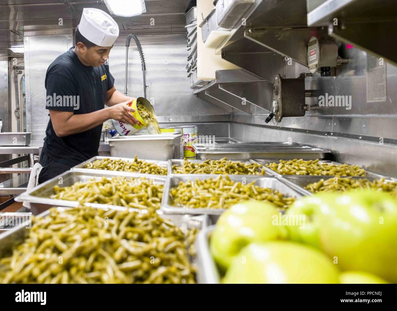 SOUTH CHINA SEA (Aug. 19, 2018) Culinary Specialist Seaman Jasta Yu, from Lake Stevens, Wash., prepares a meal for the crew in the galley of San Antonio-class amphibious transport dock USS Anchorage (LPD 23) during a regularly scheduled deployment of the Essex Amphibious Ready Group (ARG) and 13th Marine Expeditionary Unit (MEU). The Essex ARG/13th MEU is a capable and lethal Navy-Marine Corps team deployed to the 7th fleet area of operations to support regional stability, reassure partners and allies and maintain a presence postured to respond to any crisis ranging from humanitarian assistanc Stock Photo