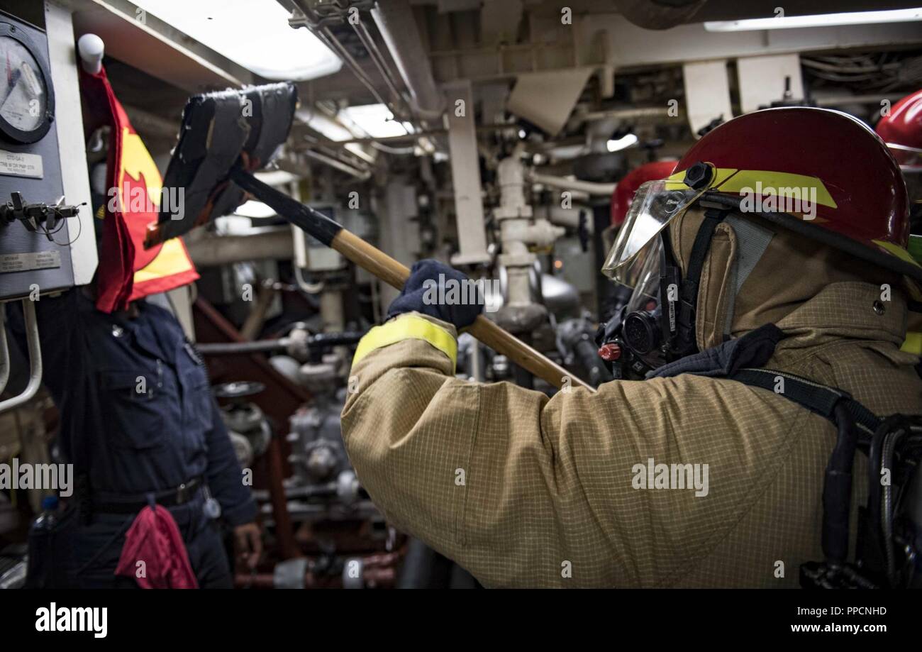 SEA (Aug. 31, 2018) Engineman 2nd Class Jonathan Martinez fights a simulated fire during a general quarters drill aboard the Arleigh Burke-class guided-missile destroyer USS Carney (DDG 64) Aug. 31, 2018. Carney, forward-deployed to Rota, Spain, is on its fifth patrol in the U.S. 6th Fleet area of operations in support of regional allies and partners as well as U.S. national security interests in Europe and Africa. Stock Photo