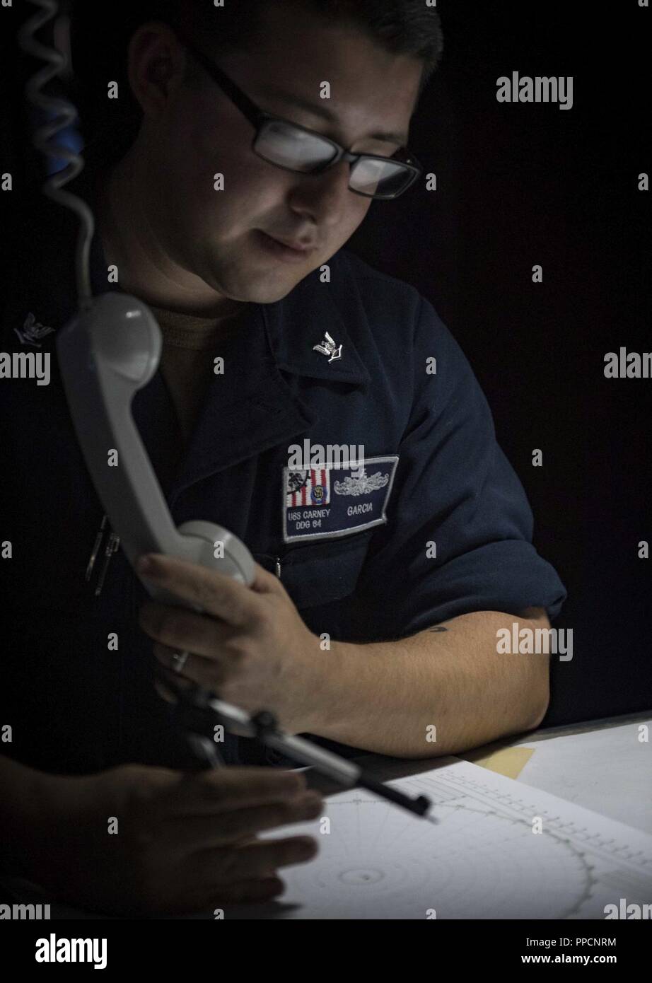 SEA (Sept. 4, 2018) Operations Specialist 3rd Class James Garcia stands watch in the combat information center aboard the Arleigh Burke-class guided-missile destroyer USS Carney (DDG 64), Sept. 4, 2018. Carney, forward-deployed to Rota, Spain, is on its fifth patrol in the U.S. 6th Fleet area of operations in support of regional allies and partners as well as U.S. national security interests in Europe and Africa. Stock Photo
