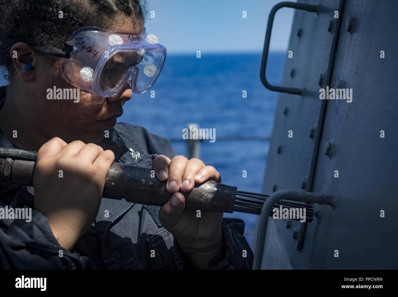 SEA (Sept. 4, 2018) Fire Controlman 2nd Class Jeniva Flemming performs topside preservation maintenance aboard the Arleigh Burke-class guided-missile destroyer USS Carney (DDG 64) Sept. 4, 2018. Carney, forward-deployed to Rota, Spain, is on its fifth patrol in the U.S. 6th Fleet area of operations in support of regional allies and partners as well as U.S. national security interests in Europe and Africa. Stock Photo