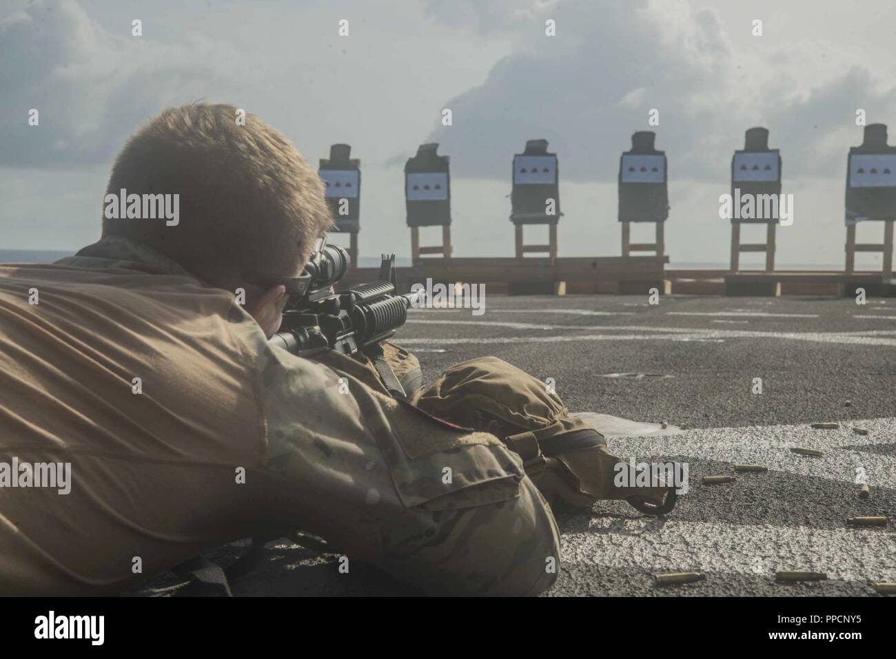 INDIAN OCEAN (Sept. 1, 2018) Marine Corps Staff Sgt. David Revels, assigned to the Marine Light Attack Helicopter detachment of Marine Medium Tiltrotor Squadron (VMM) 166, a native of Gastonia, N.C., fires an M-4 assault rifle during a small arms live-fire qualification course on the flight deck of San Antonio-class amphibious transport dock USS Anchorage (LPD 23), while on a regularly scheduled deployment of the Essex Amphibious Ready Group (ARG) and 13th Marine Expeditionary Unit (MEU). The ARG/MEU is forward-deployed to the U.S. 5th Fleet Area of Operations in support of naval operations to Stock Photo