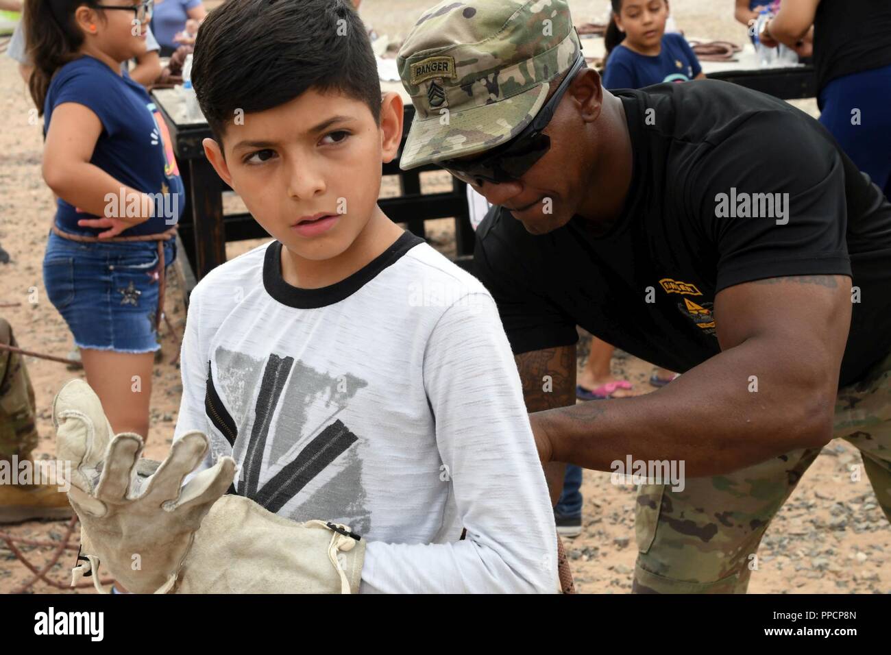 Staff Sgt. Marty Brosett, 1st Armored Division Iron Training Detachment cadre, prepares a child’s Swiss seat at the Air Assault Obstacle Course during the third annual Community Outreach Day at Fort Bliss Aug. 25. This year’s event was coordinated by the 210th RSG and the 1st Armored Division Iron Training Detachment - along with volunteers of Child Crisis Center, Big Brothers Big Sisters, and the El Paso Police Department – to mentor and interact with citizens of El Paso, Texas. Stock Photo