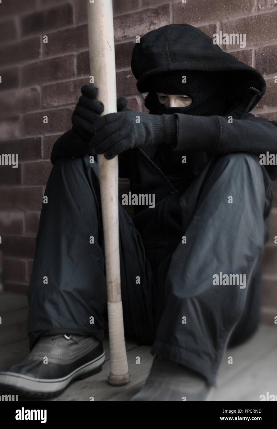 A rioter ready for troubles, is waiting with a baseball bat in his hands, ready for attack. Stock Photo