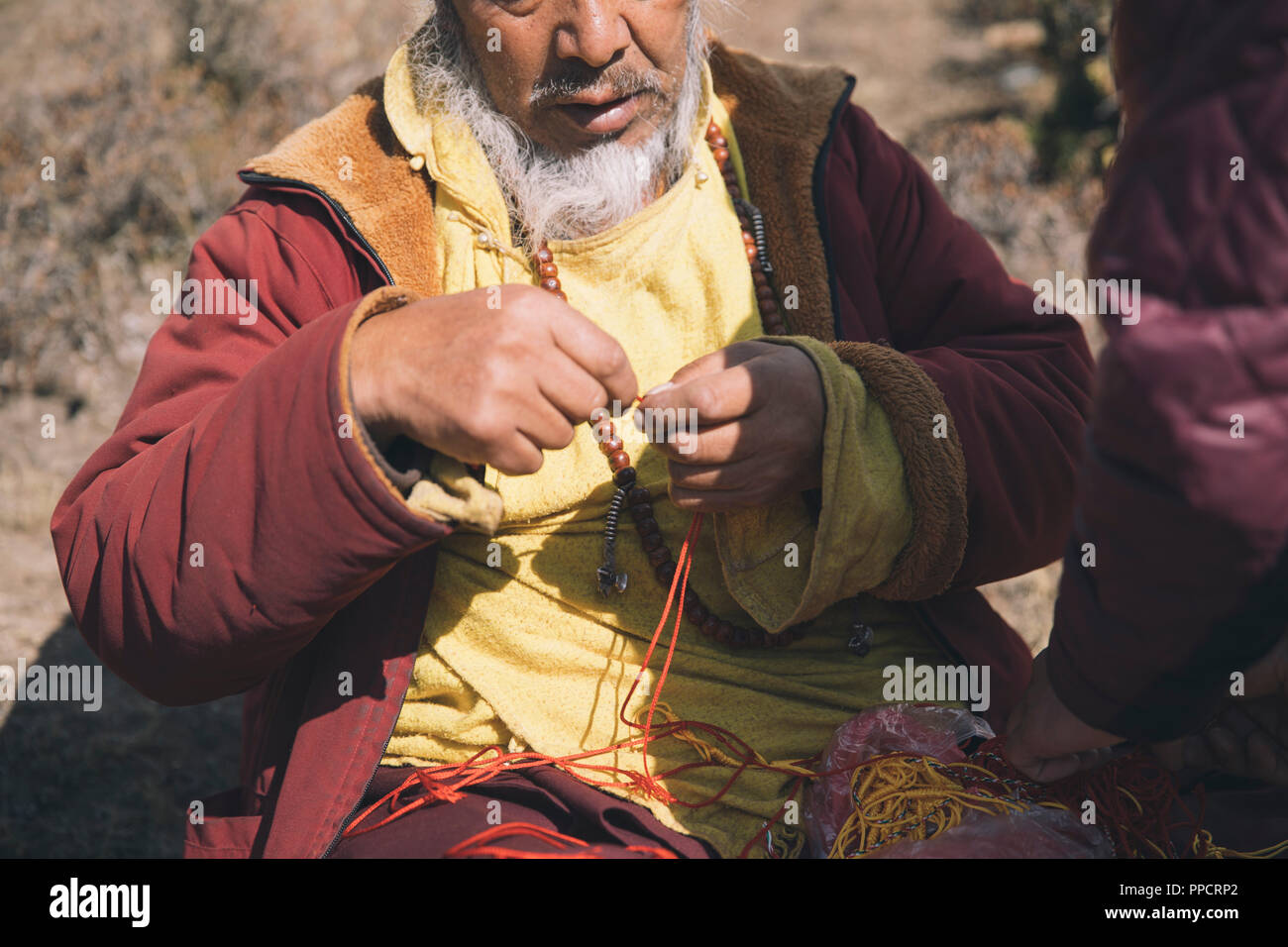 A Buddhist monk ties a prayer knot for a Himalayan trekker Stock Photo