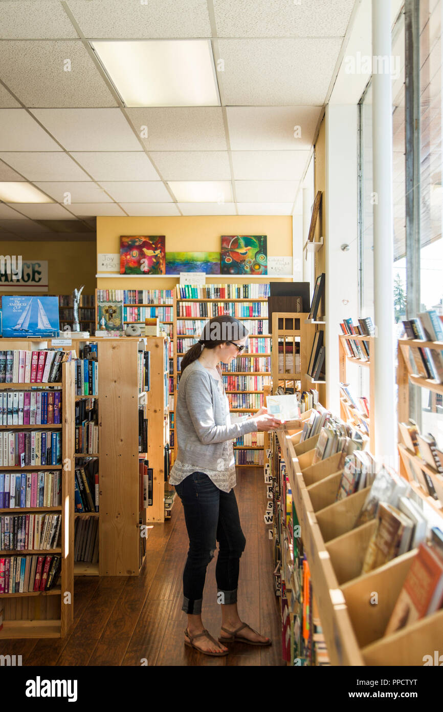 Young woman reading book in bookstore, Seattle, Washington, USA Stock Photo