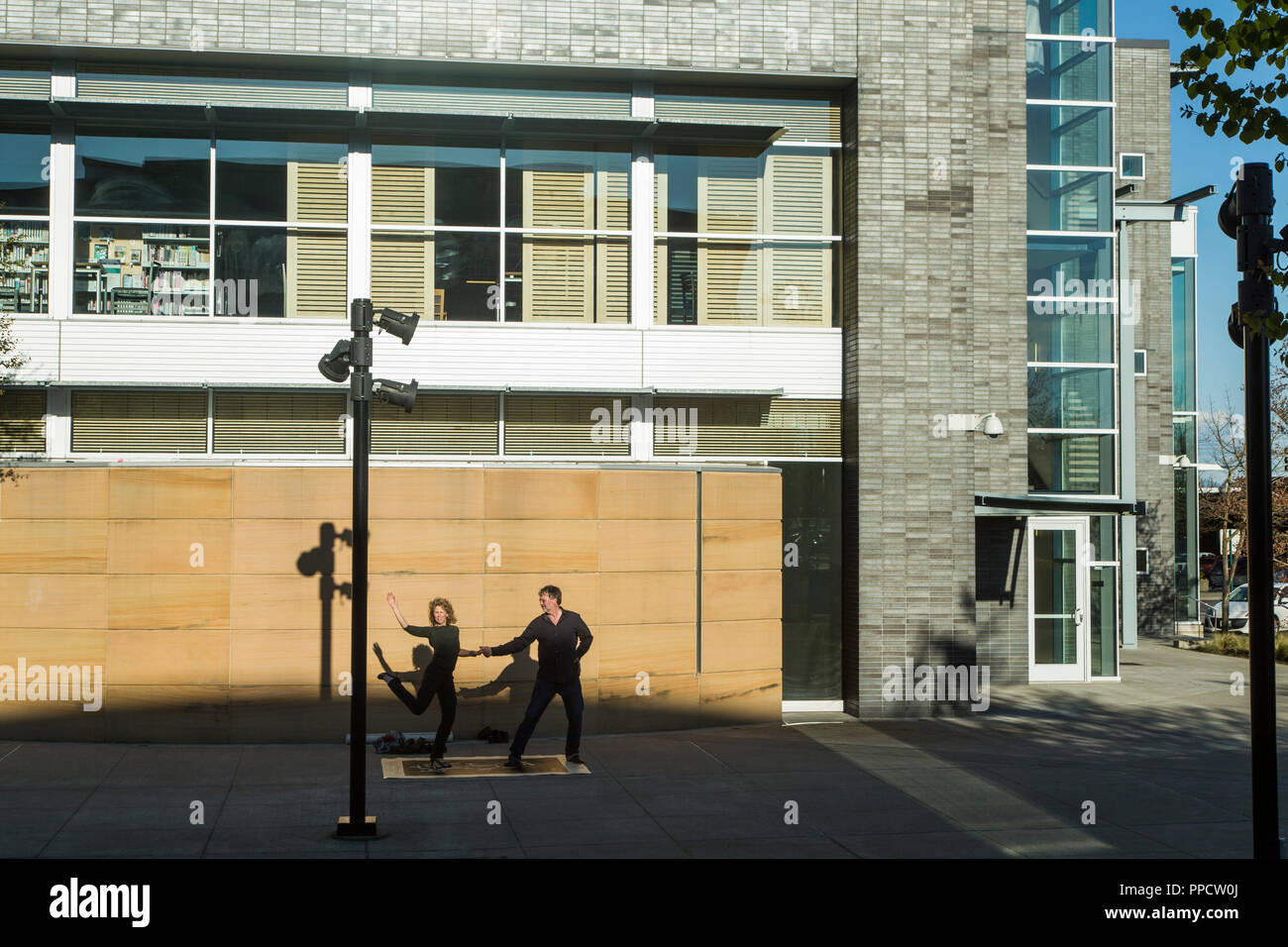 Couple dancing on pavement in front of newly constructed building, Seattle, Washington, USA Stock Photo