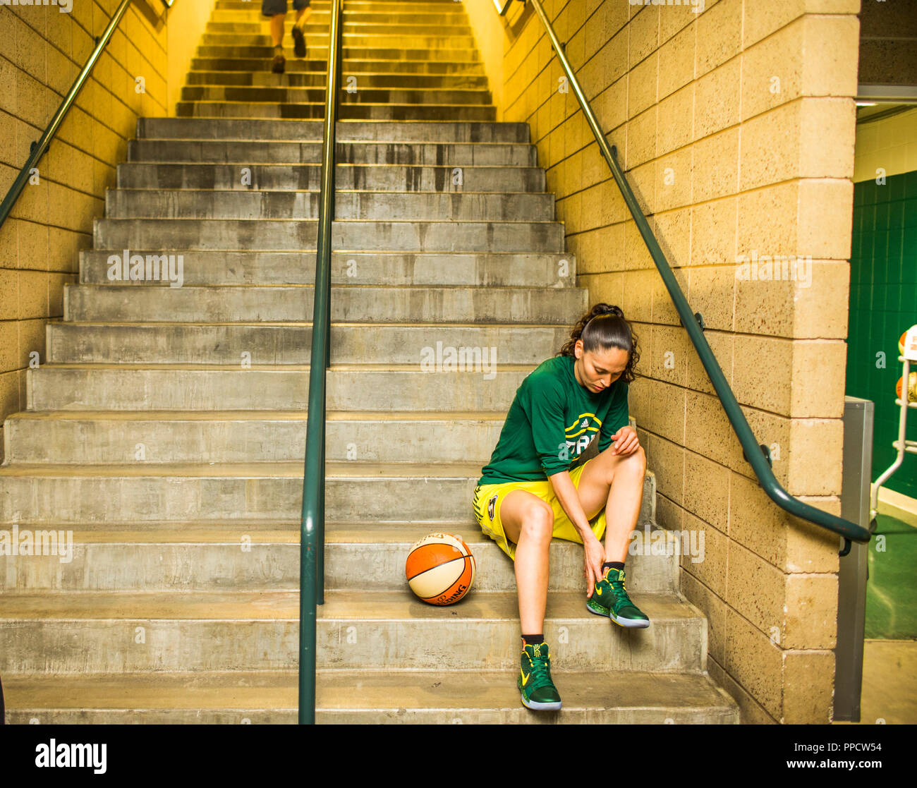Female basketball player sitting on steps and preparing for game, Seattle, Washington, USA Stock Photo