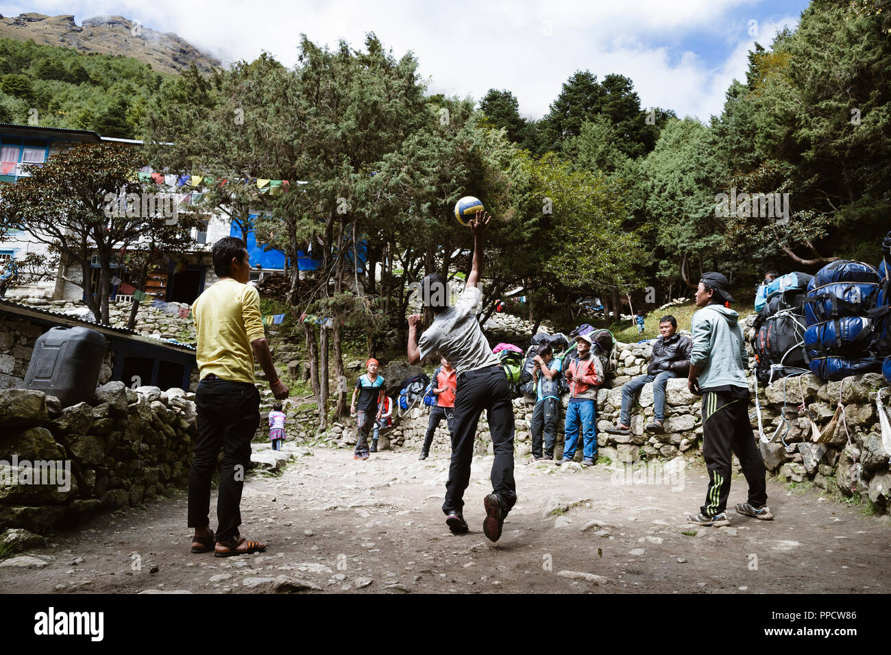 Sherpas and porters play volleyball in a Himalayan village. Volleyball is one of Nepal's favorite sports and nets can be seen all along the trails when trekking, Namche Bazaar, Solu Khumbu, Nepal Stock Photo