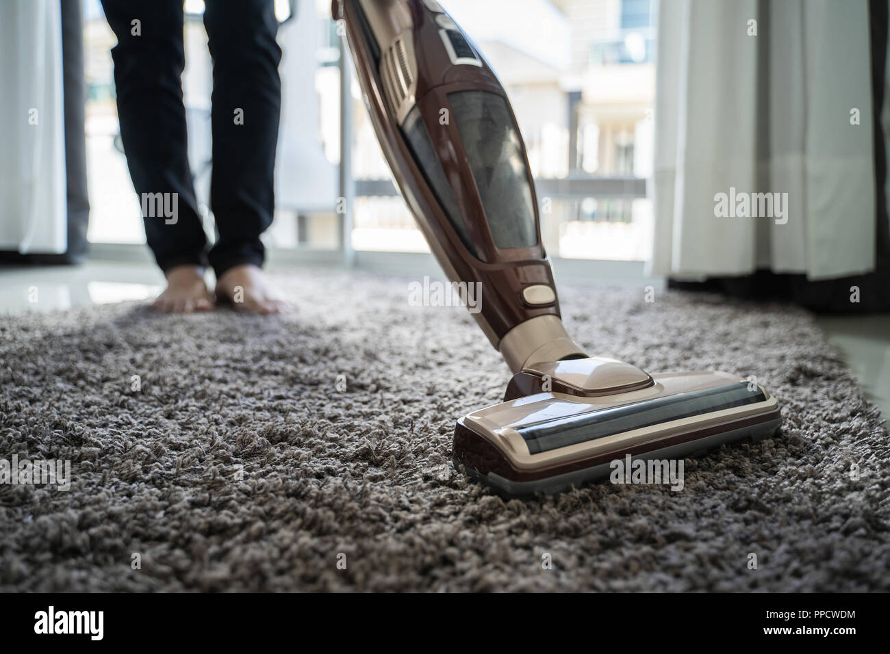 Close-up man using a vacuum cleaner while cleaning in the room Stock Photo  - Alamy