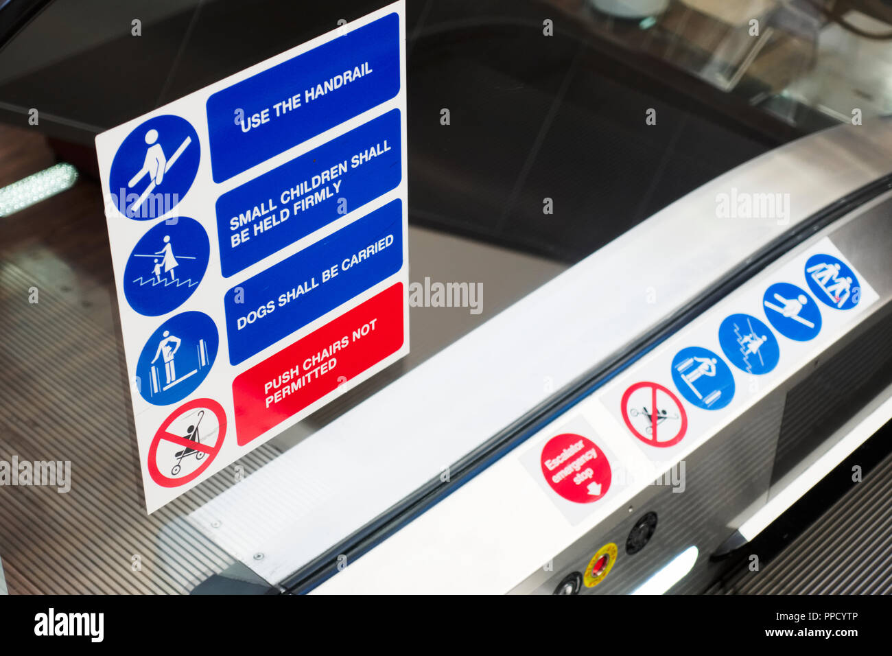 Escalator safety sign symbols close up and text on glass at top of electric lift Stock Photo