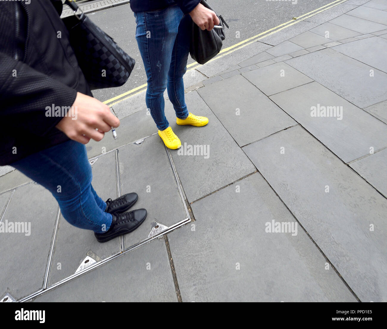 Two women smoking, one with yellow shoes, London, England, UK. Stock Photo