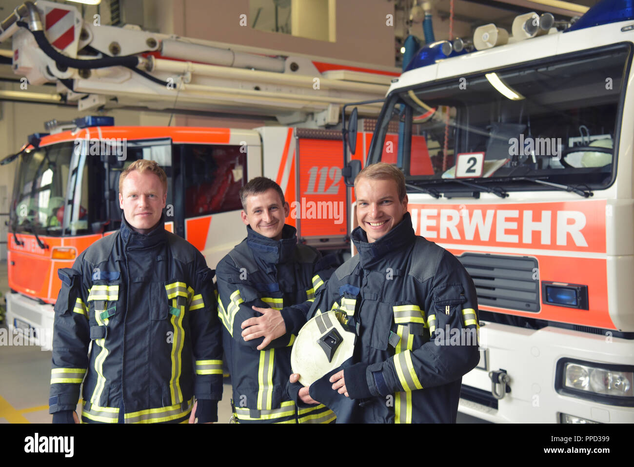 Group of firefighters at the emergency vehicle in the fire station Stock Photo
