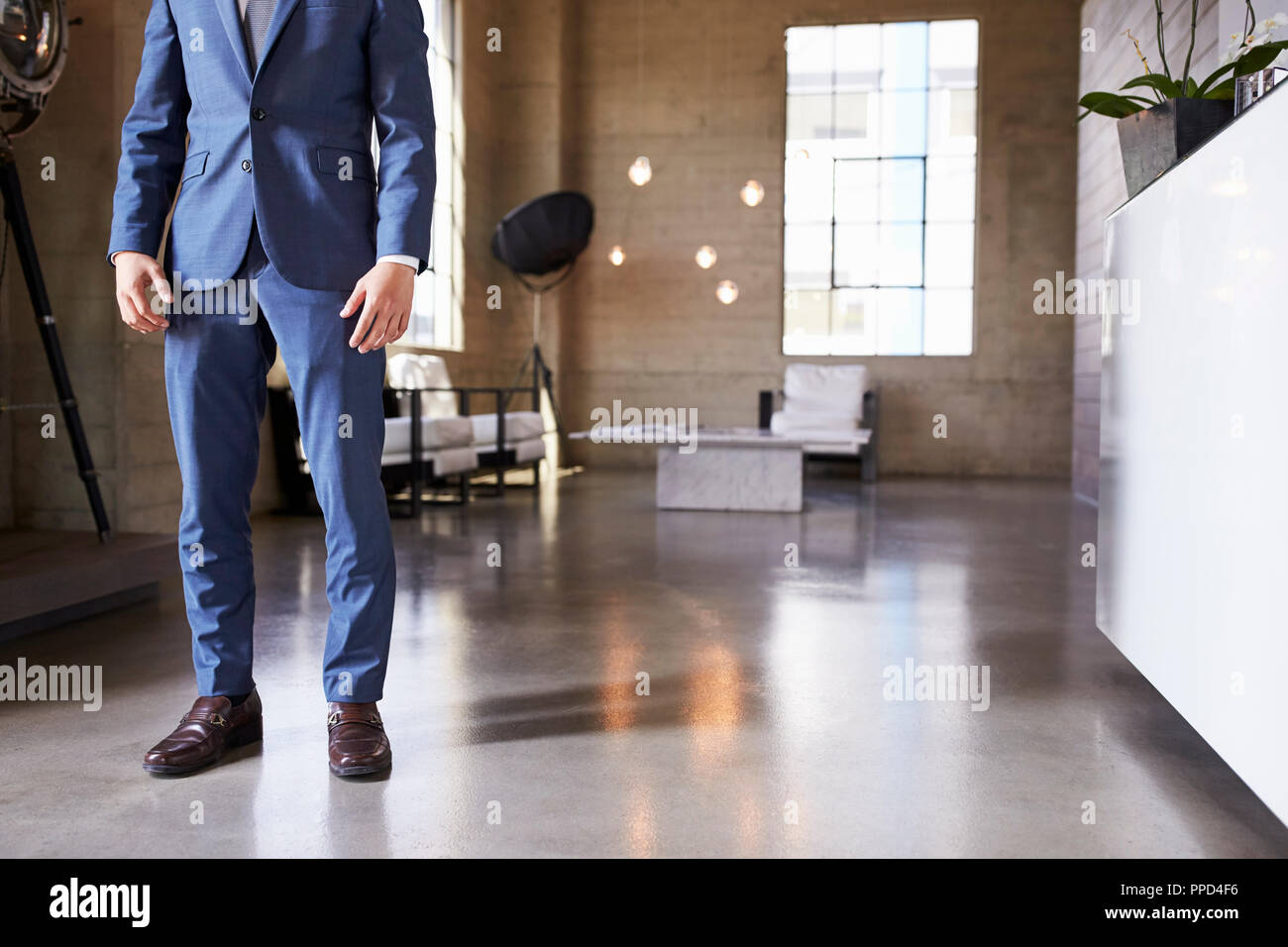 Low section of man in suit standing in modern furnished room Stock Photo
