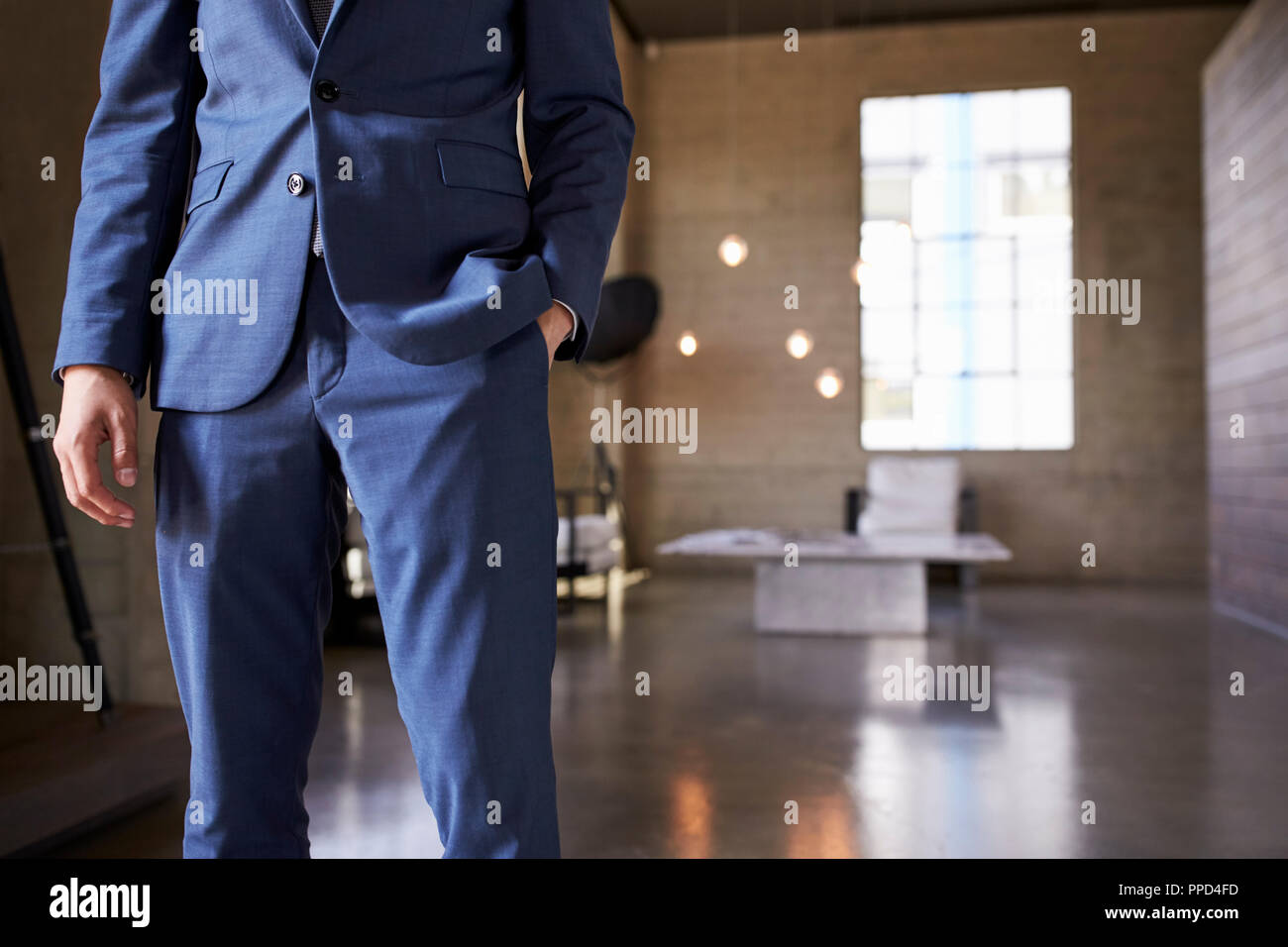 Mid section of man in blue suit standing, hand in pocket Stock Photo