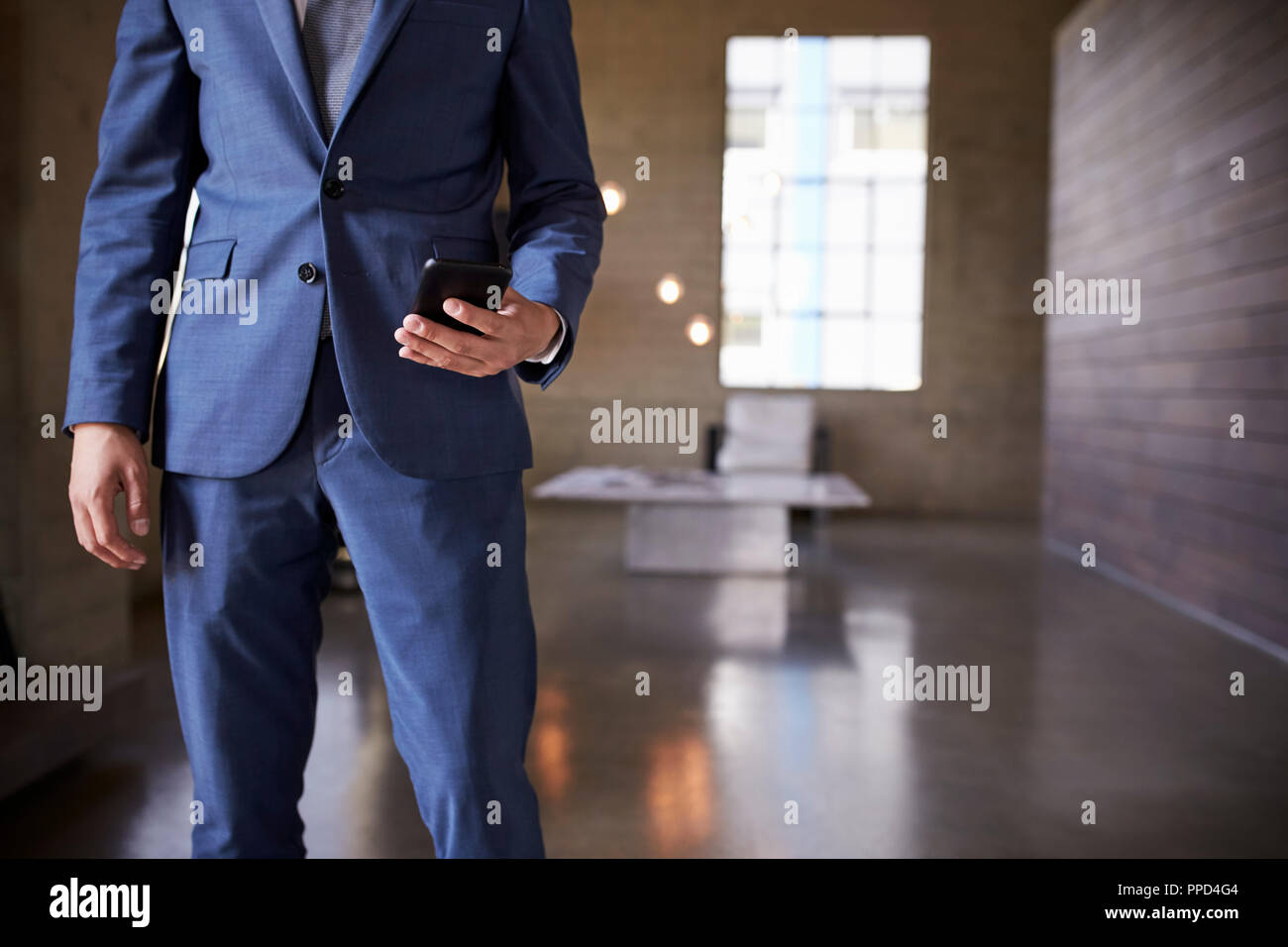 Mid section of man in blue suit using smartphone Stock Photo