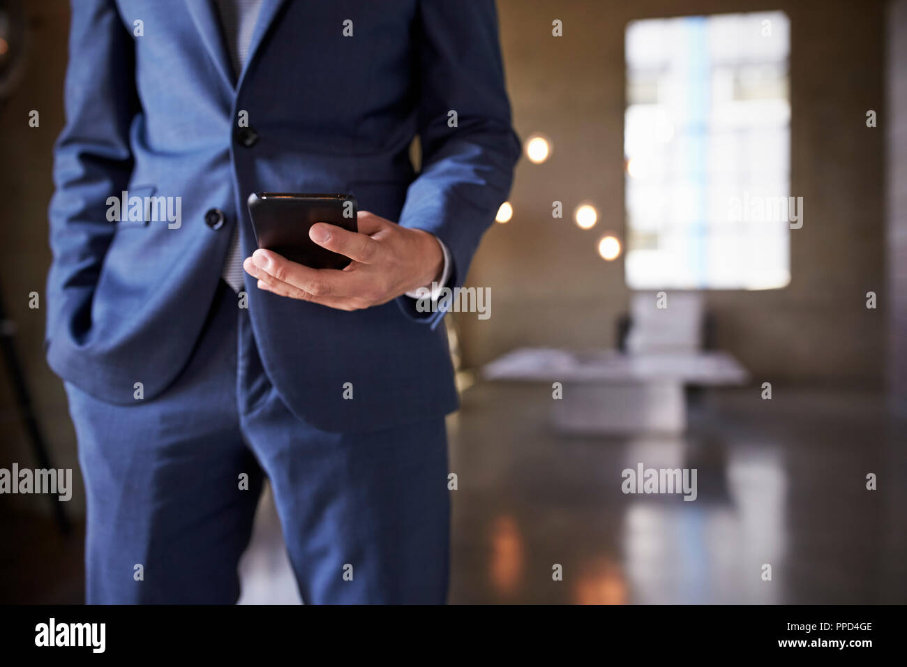 Mid section of man in blue suit using smartphone, close up Stock Photo