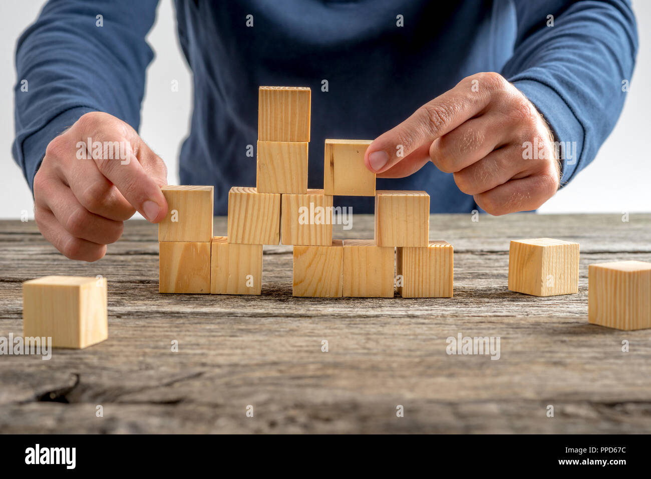 Close up Man Assembling a Tower Using Wooden Cubes on Top of a Rustic ...