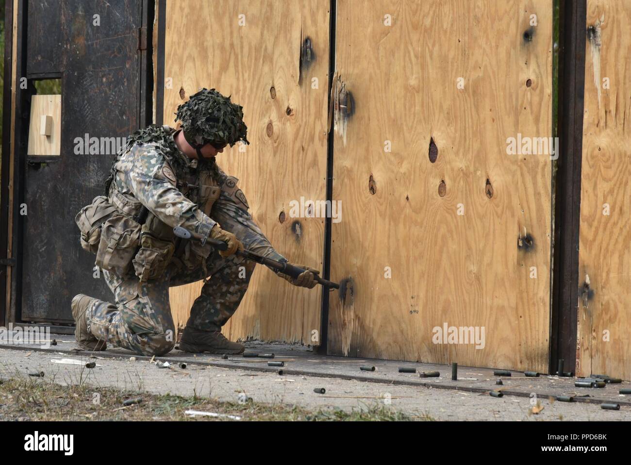 A Latvian Soldier uses an M500 shotgun to breach a door during the Urban Breach Training  at the Grafenwoehr Training Area, Germany, Aug. 29. 2018. U.S. Soldiers assigned to the 7th Army Combined Arms Training Center (CATC), 7th Army Training Command, instructed U.S. Soldiers assigned to various units across Europe, Latvian soldiers and Dutch soldiers on how to conduct urban breaching and offered new techniques for entering hostile or unknown buildings. Stock Photo