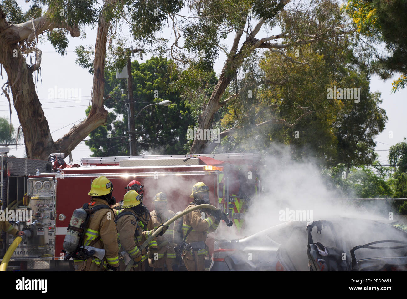 Firemen putting out a fire on a burning car in Downey, CA in 2017 Stock Photo