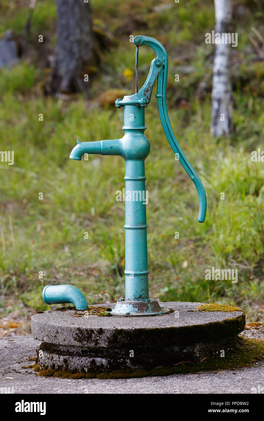 Vintage green hand operated water pump above its well. Stock Photo