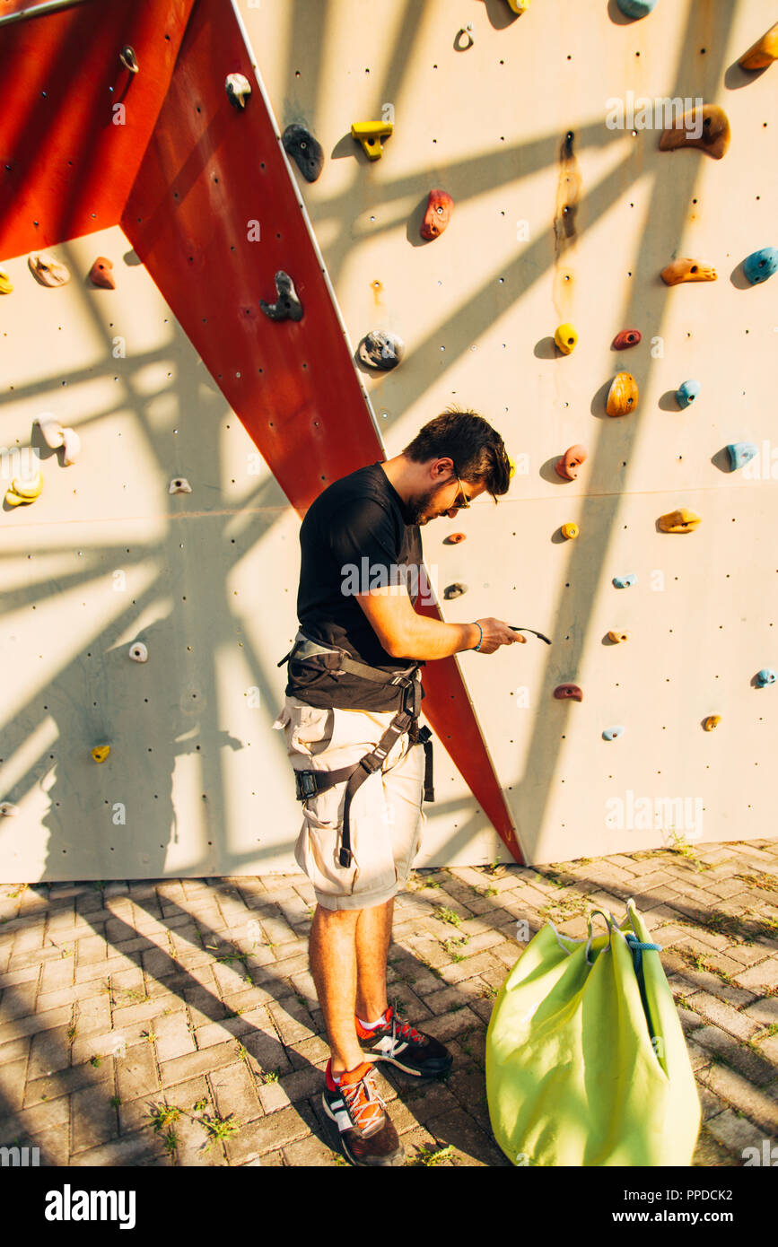 Young climber with harness belt prepare for hiking on big wall Stock