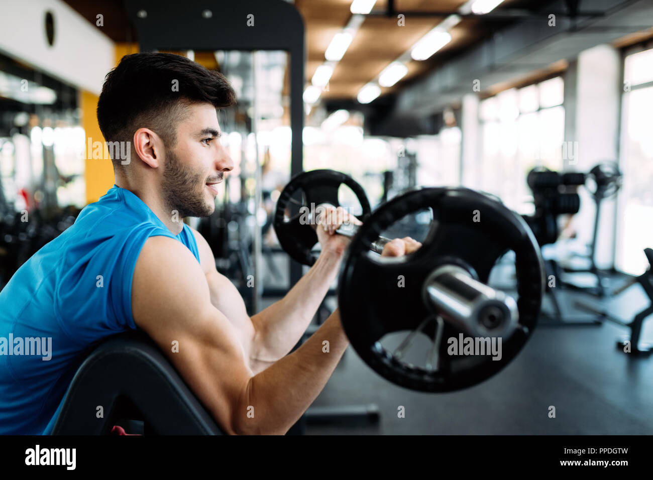 Athlete muscular bodybuilder in gym training biceps Stock Photo