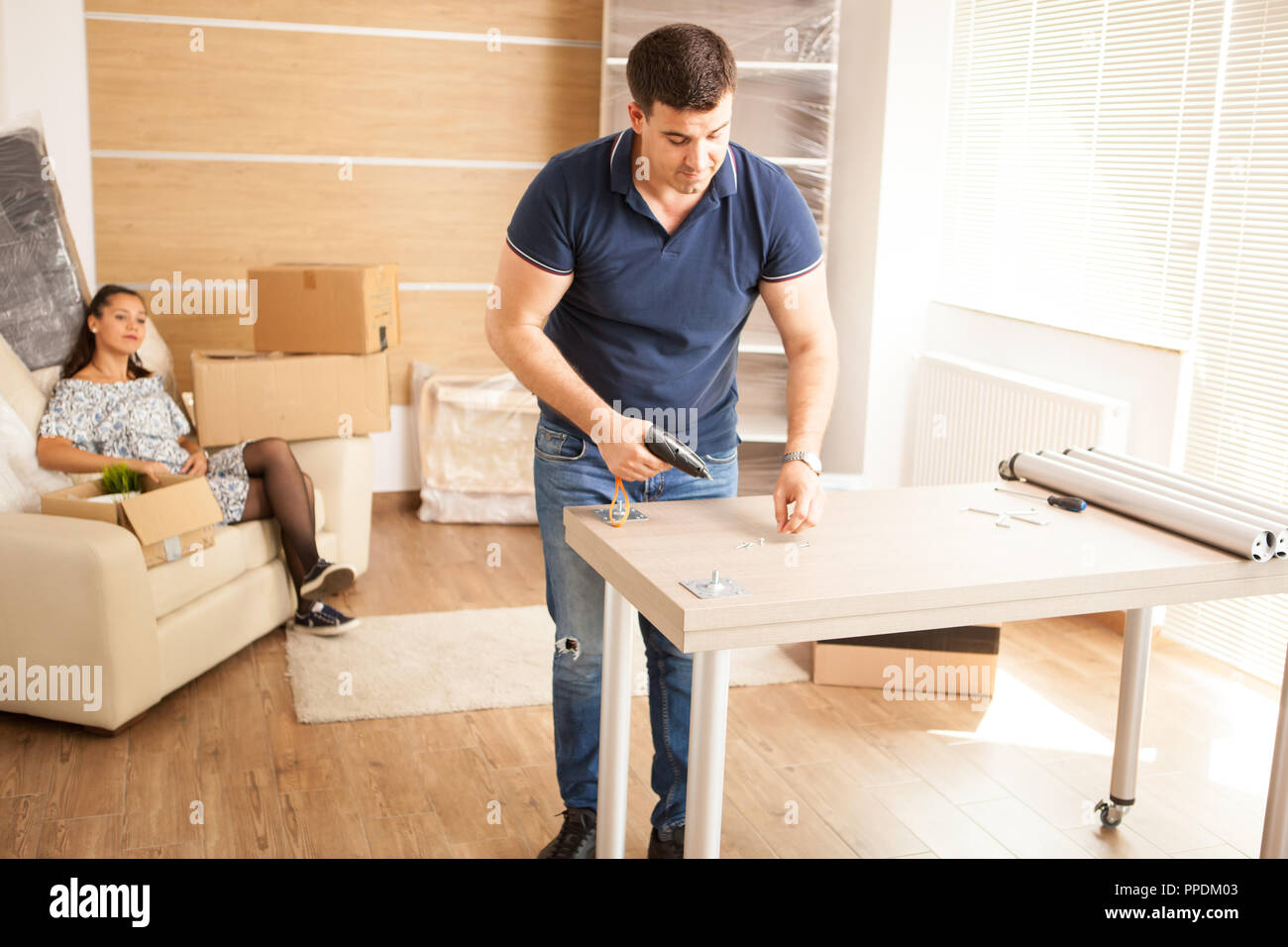 Smiling man putting together self assembly furniture in new home