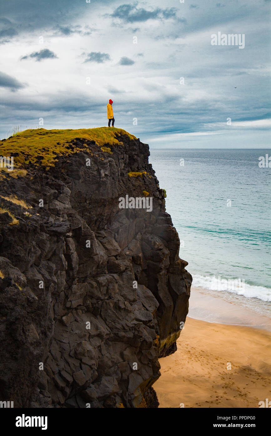 Icelandic landscape, person in yellow rain jacket. Amasing rock, Iceland. Stock Photo