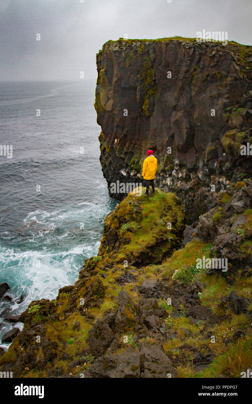 Icelandic landscape, person in yellow rain jacket. Amasing rock, Iceland. Stock Photo