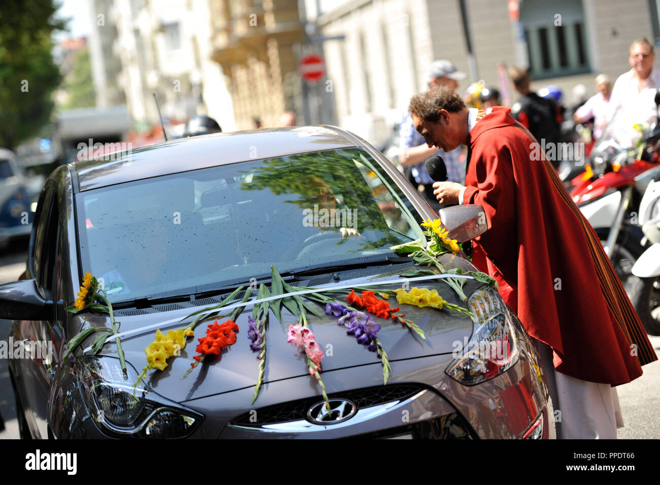 Rainer Maria Schiessler of the parish of St. Maximilian in Isarvorstadt blesses the vehicles of the attendants at the end of the worship in front of his church. The St. Christopher's Congregation Munich invites all traffic participants to receive God's blessing for 80 years. Stock Photo
