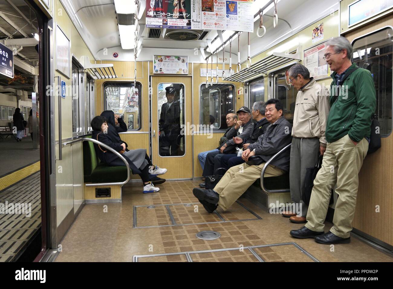 OSAKA, JAPAN - NOVEMBER 22, 2016: Passengers ride a Hankyu train in Osaka. Hankyu Corporation exists since year 1910. Stock Photo