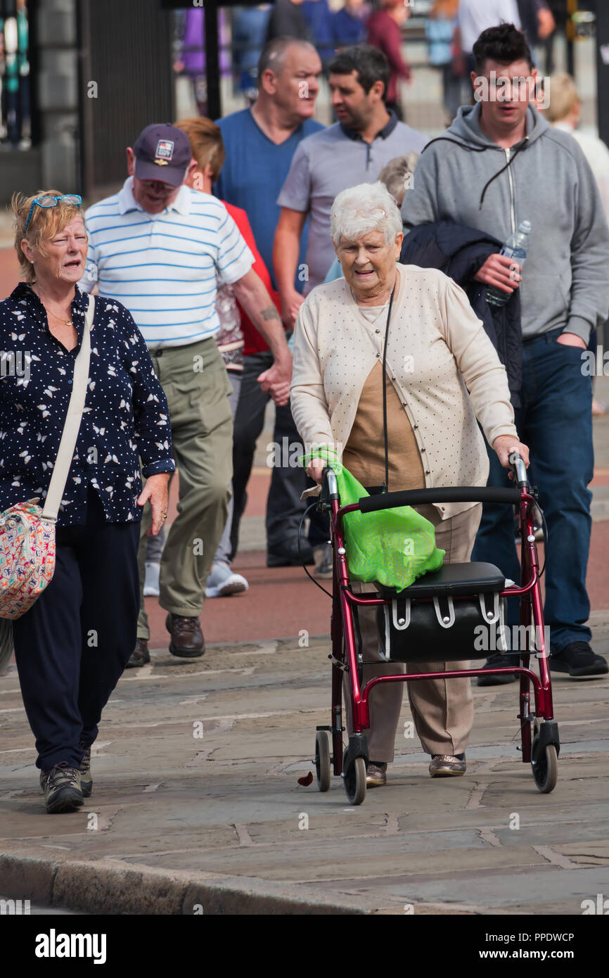 Elderly woman out walking with the use of a 4 wheel mobility rollator ...