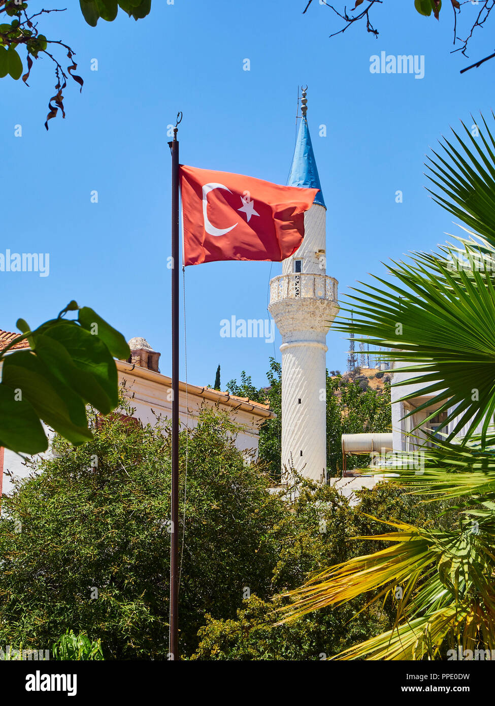 Minaret of Kelerlik Mahallesi Cami mosque with the official flag of the Republic of Turkey waving in the foreground. Stock Photo