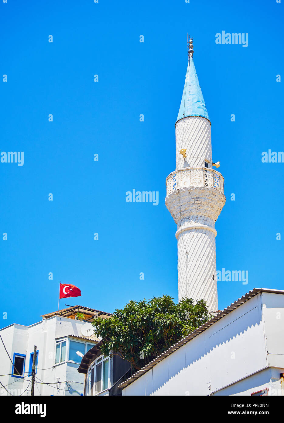 Minaret of Kelerlik Mahallesi Cami mosque with the official flag of the Republic of Turkey waving in the background. Stock Photo