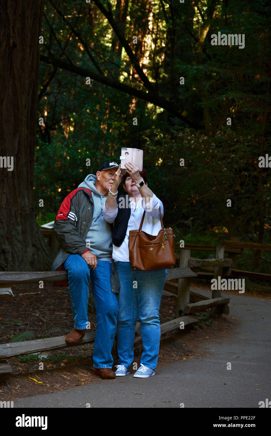 A Canadian couple on vacation take a ‘selfie’ photograph with an iPhone at Muir Woods National Monument near San Francisco, California Stock Photo