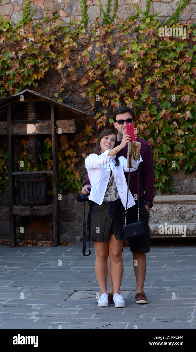 A youug couple on vacation in California take a ‘selfie’ photograph with a smartphone at Castello di Amorosa Winery Stock Photo