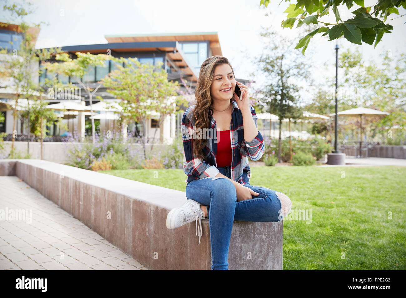 Female High School Student Talking On Mobile Phone Outside College Buildings Stock Photo